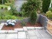 Garten-Neugestaltung Polierte und gestockte Granitstelen (grau und anthrazit), Douglasie-Holzelemente mit Edelstahl-Beschlägen sowie Neubepflanzung mit Rollrasen